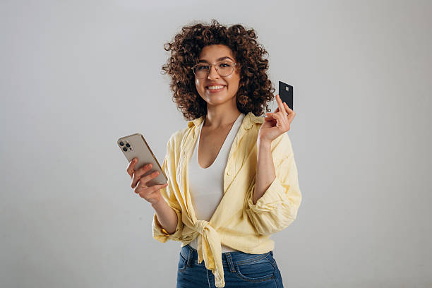 Online payment by using phone and credit card. Beautiful woman is in the studio stock photo