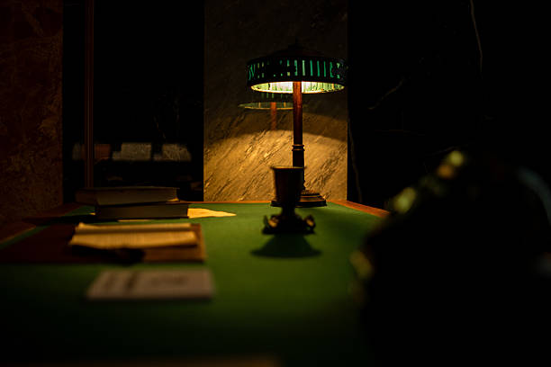 istock Warm Glow From a Vintage Lamp Illuminates a Dark Table Set With Books and Documents in a Quiet Study Room at Night 2222025811