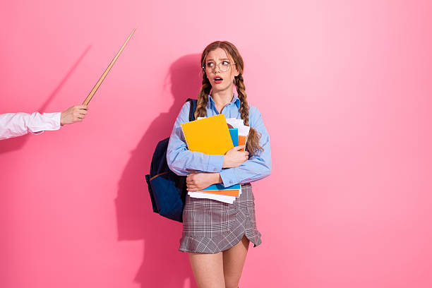istock A young female student in a school outfit holding notebooks while expressing surprise against a pink background 2222027852