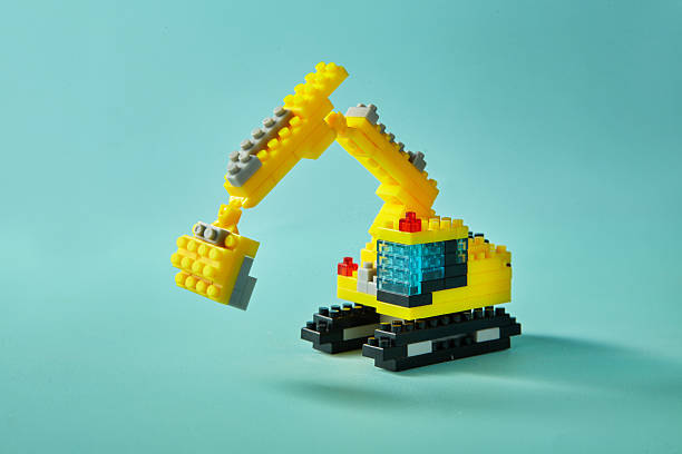 Asmall yellow excavator toy assembled on cyan background