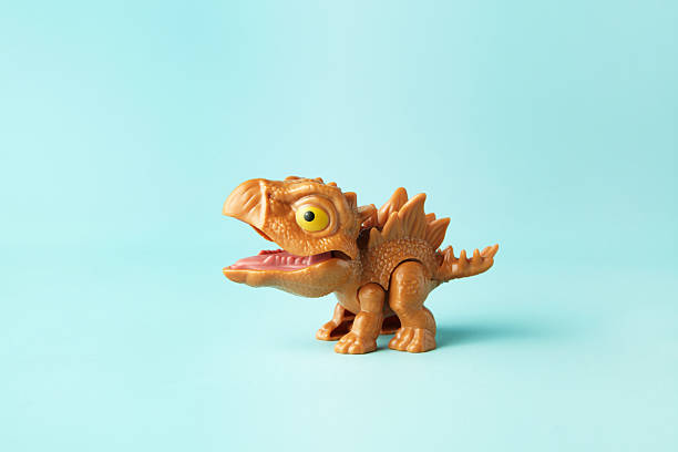 Small and cute plastic stegosaurus toy in action on cyan background