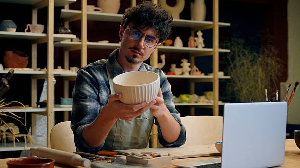 istock Caucasian man sculptor potter online laptop shopping in pottery workshop create handmade ceramics small business owner sale craft art male guy craftsman designer sell handcraft bowl crockery stoneware 2222034664