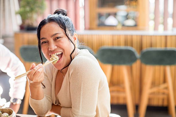 Smiling Filipino woman eating a traditional Dim Sums