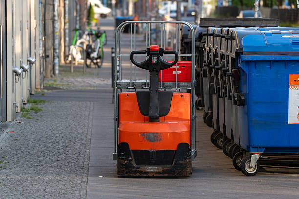 istock Electric pallet jack parked on a sidewalk next to blue and black garbage bins. 2222038051