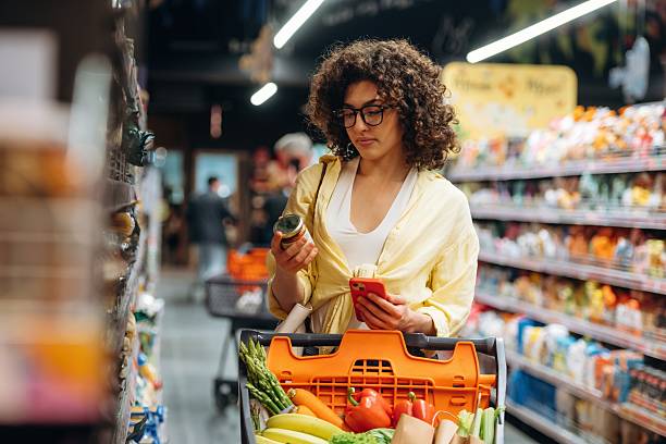 Fruits and vegetables in the cart. A beautiful woman is in the grocery store stock photo