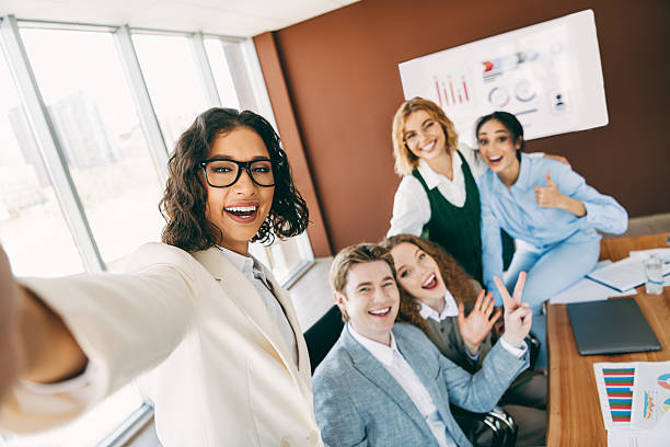 istock Young diverse coworkers in formal attire taking selfie in modern office showcasing teamwork and positive collaboration 2222039612