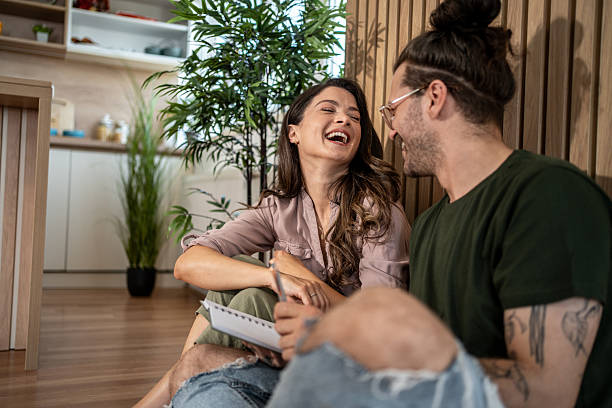 istock Young couple laughing together while reading notes at home 2222039950