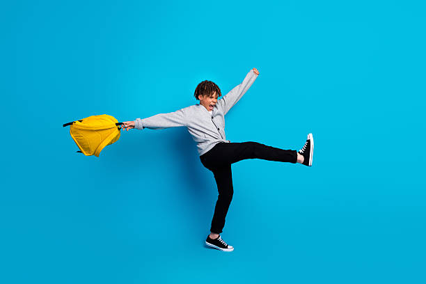 istock Energetic student with yellow backpack demonstrating happiness and enthusiasm on blue background, classroom spirit 2222040361