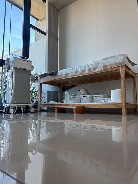 beauty treatment room in spa clinic with massage table and equipment treatment room in spa clinic with table, towels, equipment, with sunlight through large window. hhh stock pictures, royalty-free photos & images