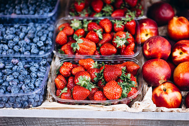 Fresh strawberries, nectarines, and blueberries at an outdoor summer market.