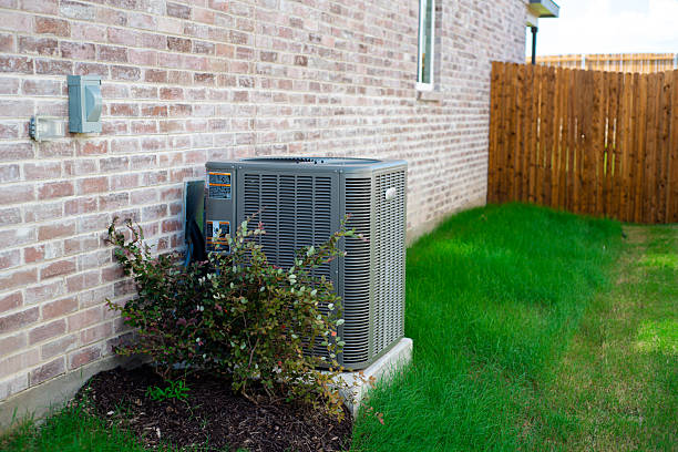 istock Outdoor HVAC unit and wall mounted electrical boxes installed alongside modern brick home, clean siding and windows, green grass landscaping shrub, privacy fence, disconnect switch, utility meter 2222043529