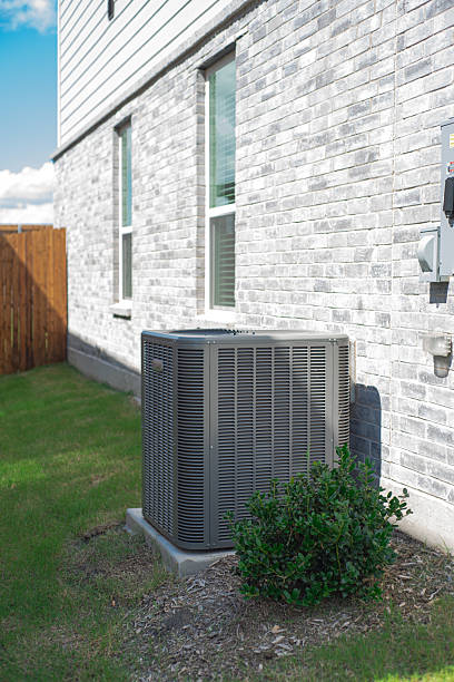 istock Outdoor HVAC unit and wall mounted electrical boxes installed alongside modern brick home, clean siding and windows, green grass landscaping shrub, privacy fence, disconnect switch, utility meter 2222043638