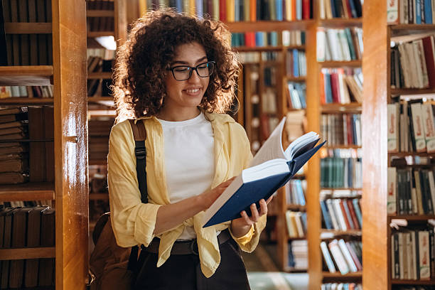 istock Reading the book. Beautiful woman is in the library 2222044497