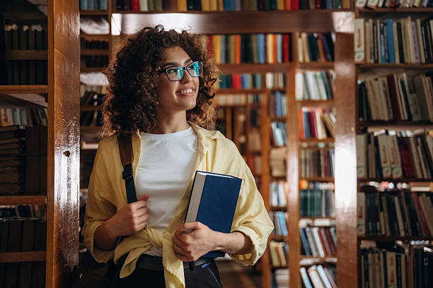 istock Standing and smiling. Beautiful woman is in the library 2222044528