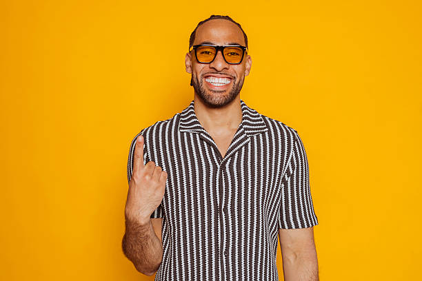 istock Smiling young man pointing up with index finger on yellow background 2222047507