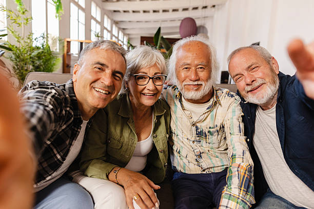 istock Group of happy senior friends taking selfie on sofa 2222048028