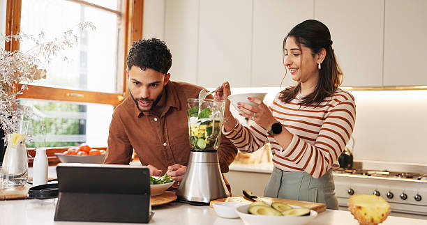 Tablet, couple and cooking with blender in home, online tutorial and web for smoothie instructions. People, vegetables and electric machine for organic shake, reading and food network for support