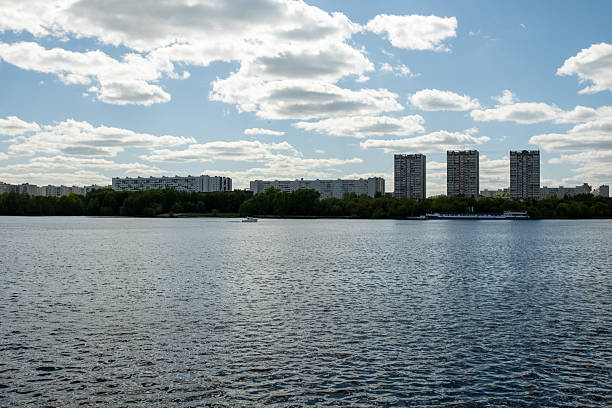 istock Serene View of Urban Skyline Over Tranquil River With Scattered Clouds and Lush Greenery Nearby 2222050092