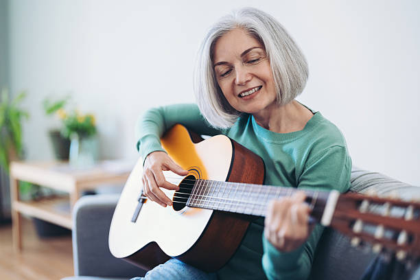 istock Mature woman playing guitar at home 2222051536