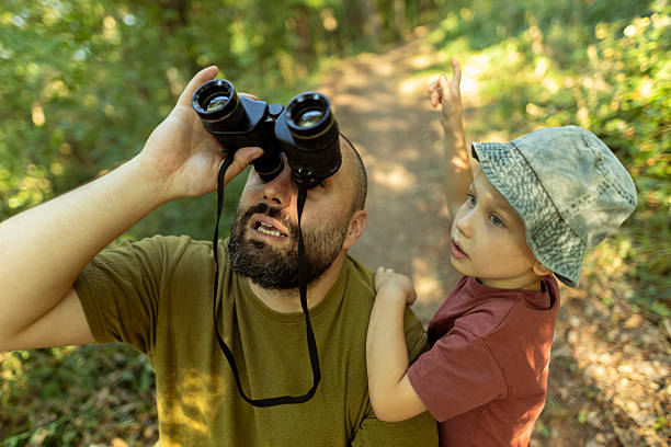 istock Father looking through binoculars while his son points and tries to show him where he spotted the birds with his bare eyes. A heartfelt moment of connection and curiosity in nature. 2222059477