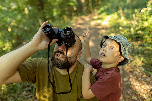 istock Father looking through binoculars while his son points and tries to show him where he spotted the birds with his bare eyes. A heartfelt moment of connection and curiosity in nature. 2222059494