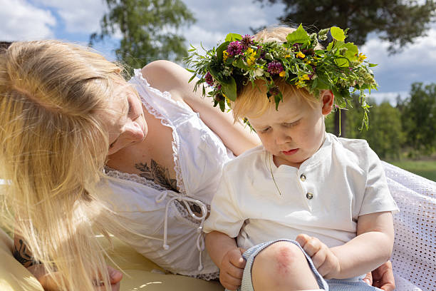 Close-up of a blond child wearing a colorful flower crown, and his mother.