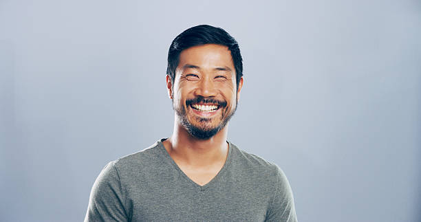 istock Asian man, happy and studio portrait with creative employee, pride and confident for freelance career. Writer, freelancer or author with professional headshot by mockup space on blue background 2222063863