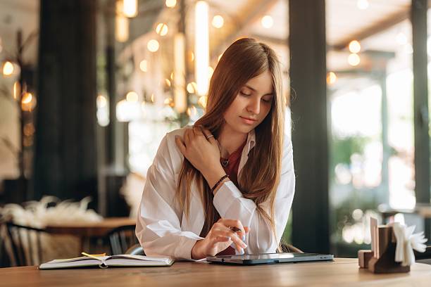 istock Using digital tablet, sitting, front view. Young woman is in the cafe at daytime 2222064952