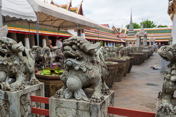 Mythological being and statue in wall at thai temple in Laphun province. Statue uis on wall at ewntrance to temple Wat Phra Phutthabat Huai Tom in  Li District, Lamphun. In background are trees
