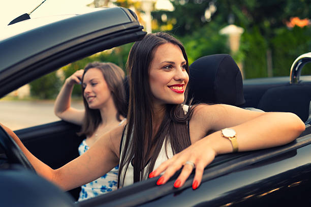 istock Two young happy women driving car on vacation 2222065603