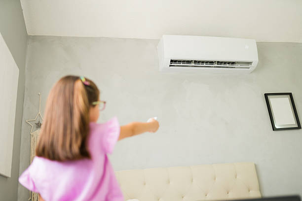 istock Girl operating air conditioner remote control in bedroom 2222067446