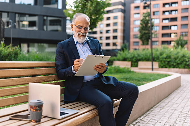 istock Senior man working on tablet outdoors with laptop 2222075124