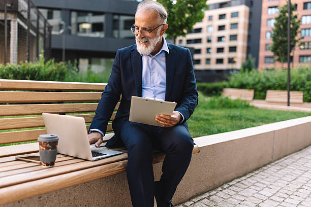 istock Senior man using laptop and clipboard in park 2222075252