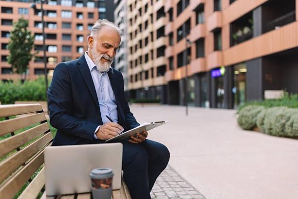 istock Joyful senior man enjoying coffee while working outdoors 2222075374