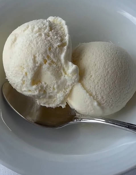 istock Delicious Vanilla Ice Cream Scoops in a White Bowl with Silver Spoon, on a soft fabric surface 2222077542