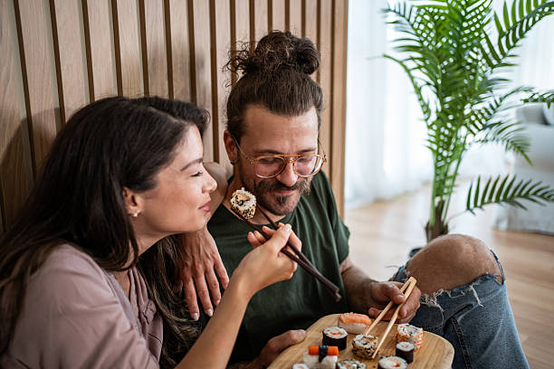istock Young couple sharing sushi in their modern apartment 2222078371