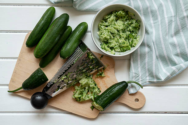 Grated and whole cucumber on cutting board