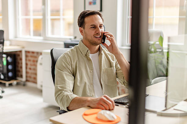 istock Professional adult engaged in a phone conversation while working at a modern office desk 2222086007