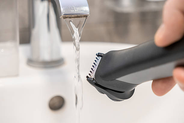 istock Person's hand cleans a modern electric beard trimmer under running tap water in a bright bathroom sink, highlighting personal grooming hygiene and product maintenance 2222087129