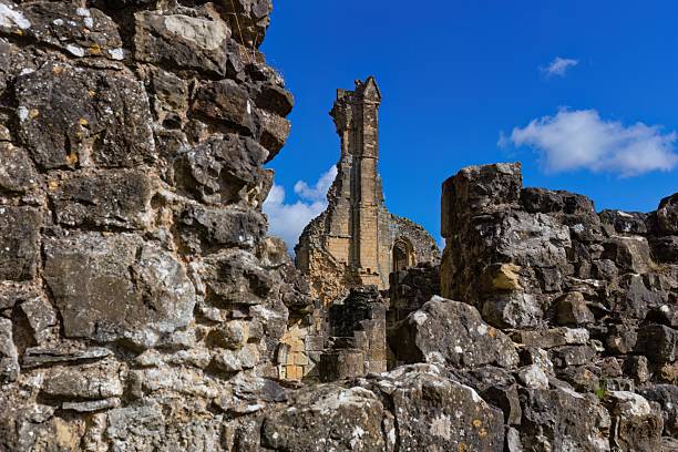 A spike stands framed by ancient stone ruins under a bright blue sky at Byland Abbey - North Yorkshire - United Kingdom