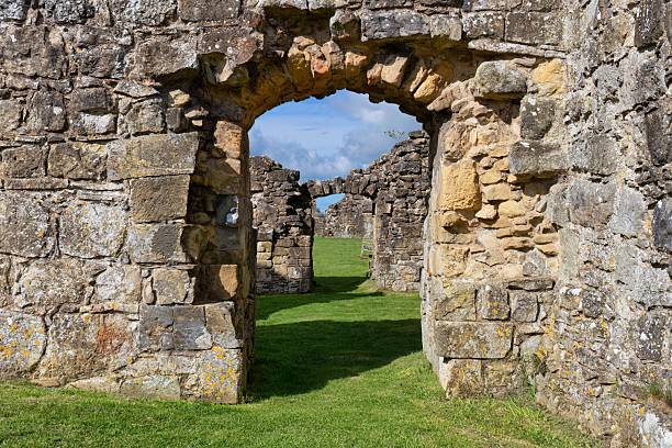 istock A weathered stone archway leads to a grassy path amidst ruins. 2222089278