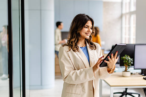 istock Young adult in modern office engages with tablet while colleagues collaborate in background during work hours 2222089747