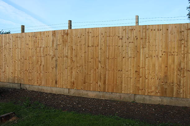 istock Wooden Privacy Fence with Secure Barbed Wire Installation in a Garden Setting 2222096391
