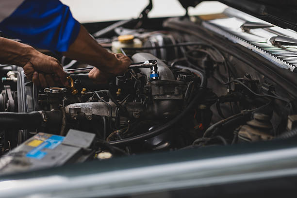 istock Auto mechanic repairing engine using wrench in garage. Mechanic in a jumpsuit fixes a car engine in a garage workshop. 2222097089