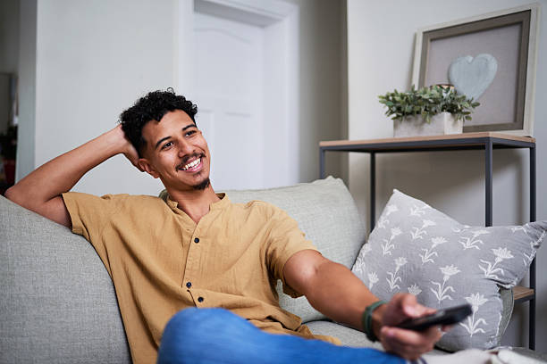 istock Smiling Man Relaxing on a Couch While Holding a Remote Control in a Cozy Living Room 2222103140