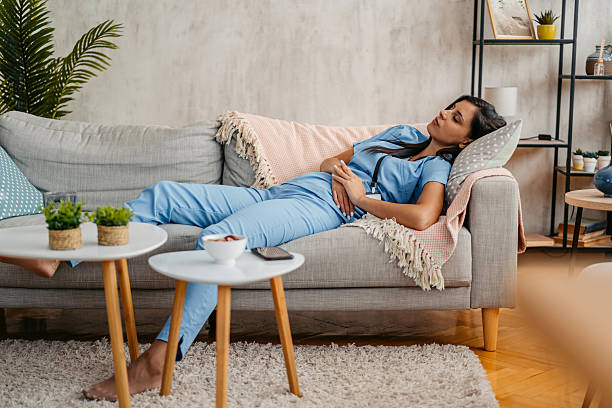 istock Tired Young Nurse Falling Asleep On The Sofa At Home 2222104181
