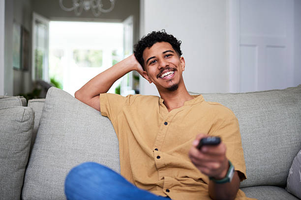 istock Relaxed Young Man Smiling and Watching Television in a Cozy Home Setting 2222104601