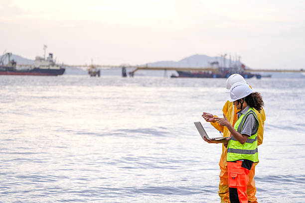 istock Two field scientists in PPE gear analyzing seawater samples using test tubes and a laptop. Environmental monitoring and pollution control on the coastline are depicted. 2222108057