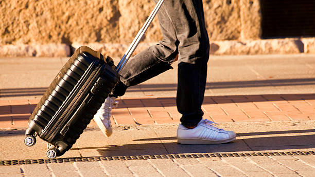 Man travelling, walking on sidewalk at dusk with his trolley. Vacations. Madrid.