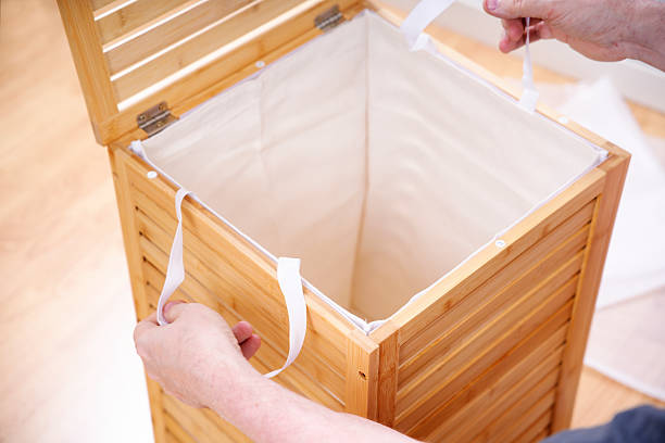 istock Person installing cloth laundry hamper liner in wooden bamboo frame 2222116069